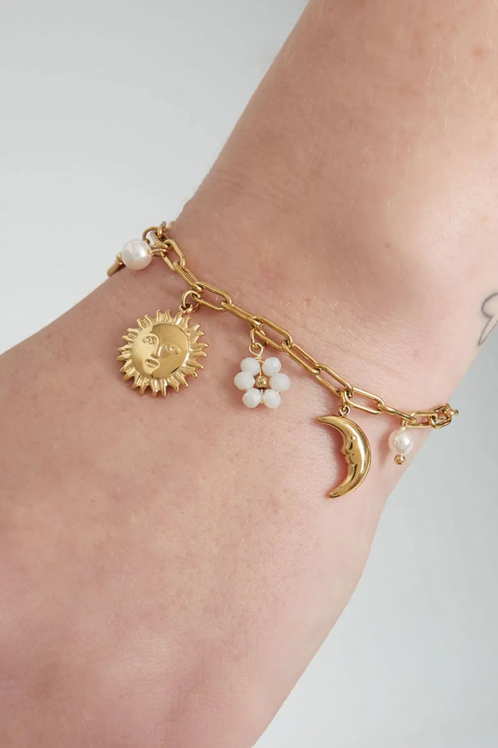 goudkleurig bedel armbandje met zonnetje en maan om pols